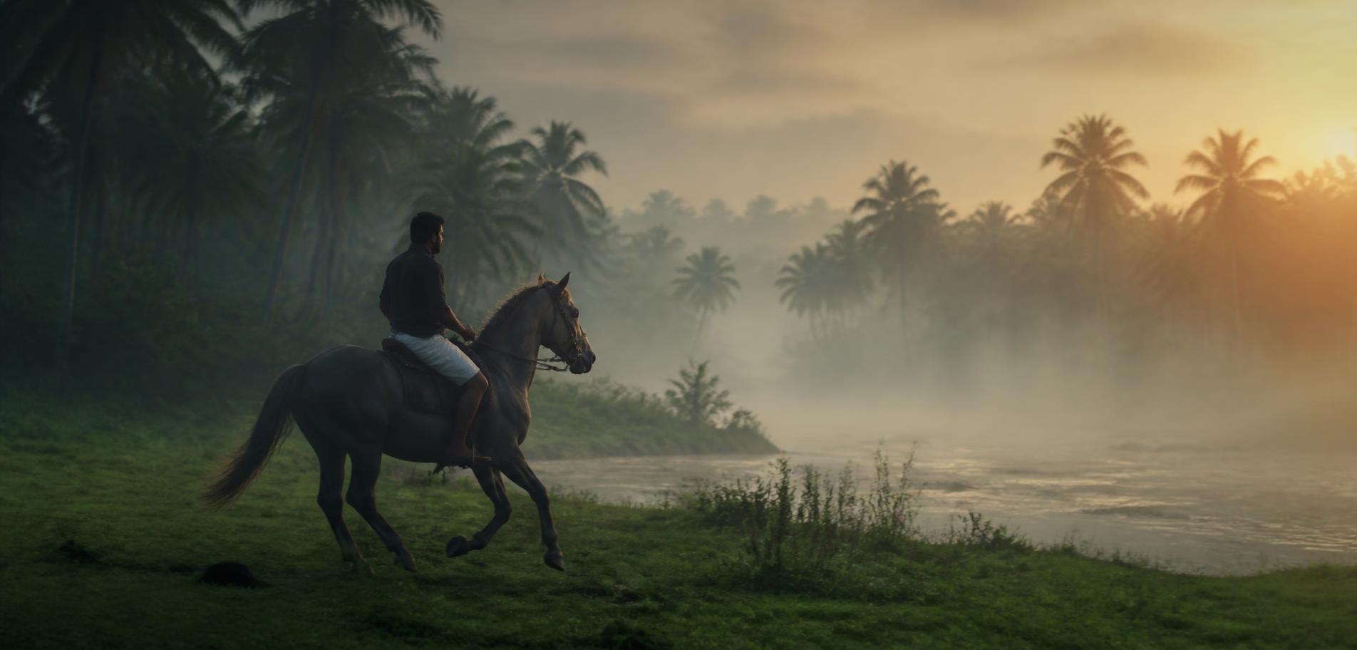 Horse and rider cantering along a misty riverbank at sunrise